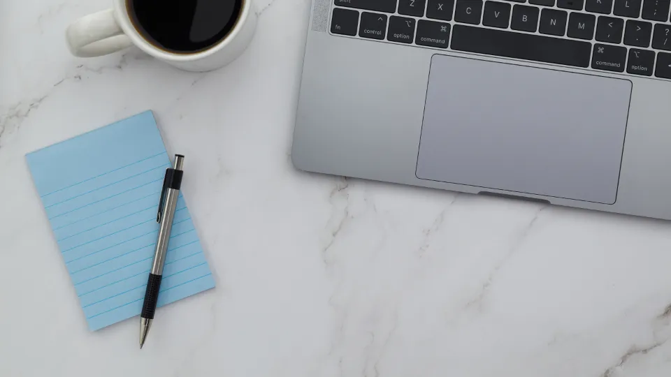 Notebook, šálka kávy a zápisník na stole, spracovanie dopytov z webu